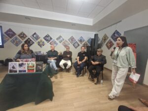 Moderadora dempeus durant una trobada literària del Festival Basalt 2026, amb diversos participants i llibres exposats.